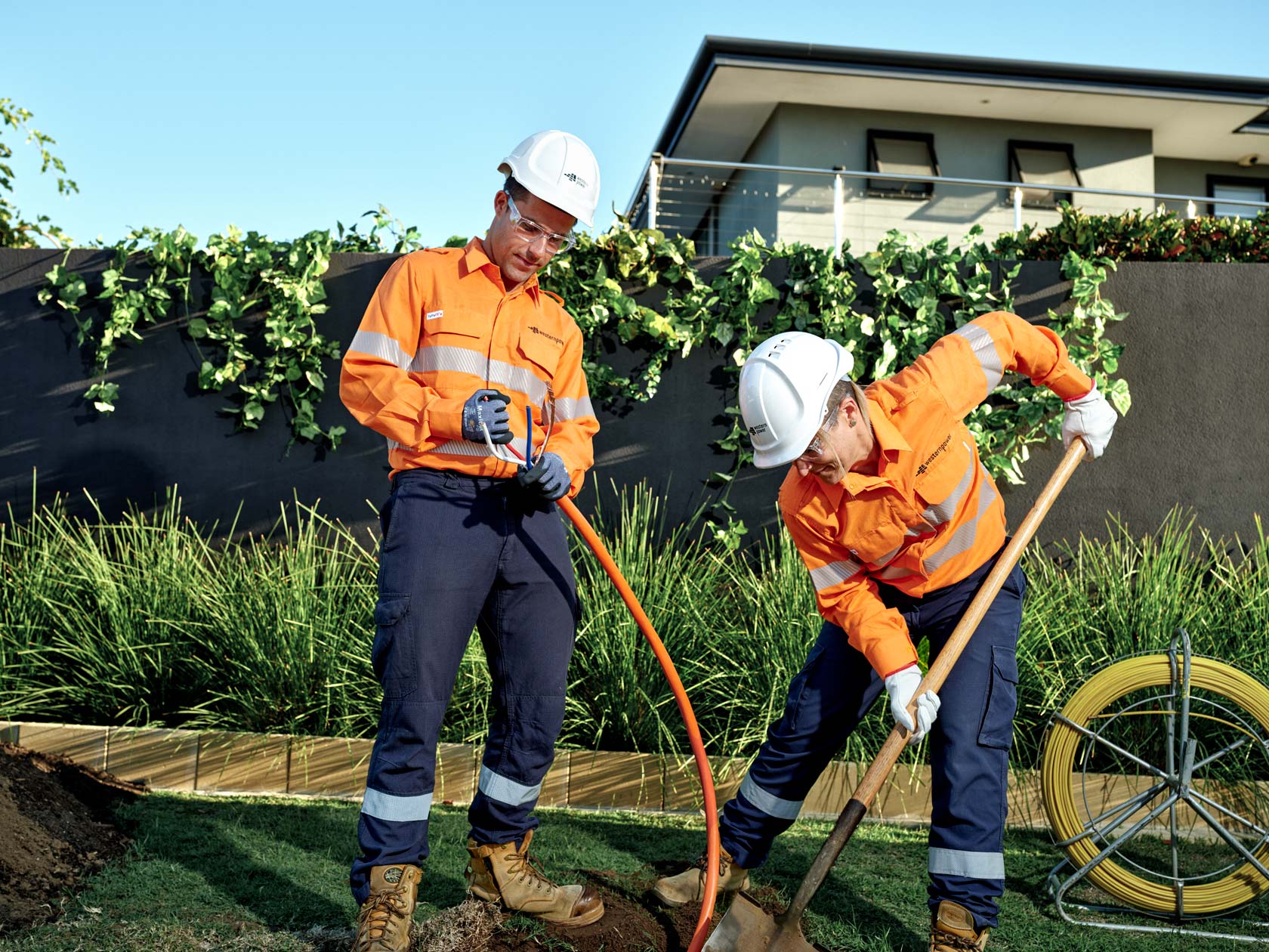 Utility workers installing underground power cables in a residential area in Western Australia for network reliability.