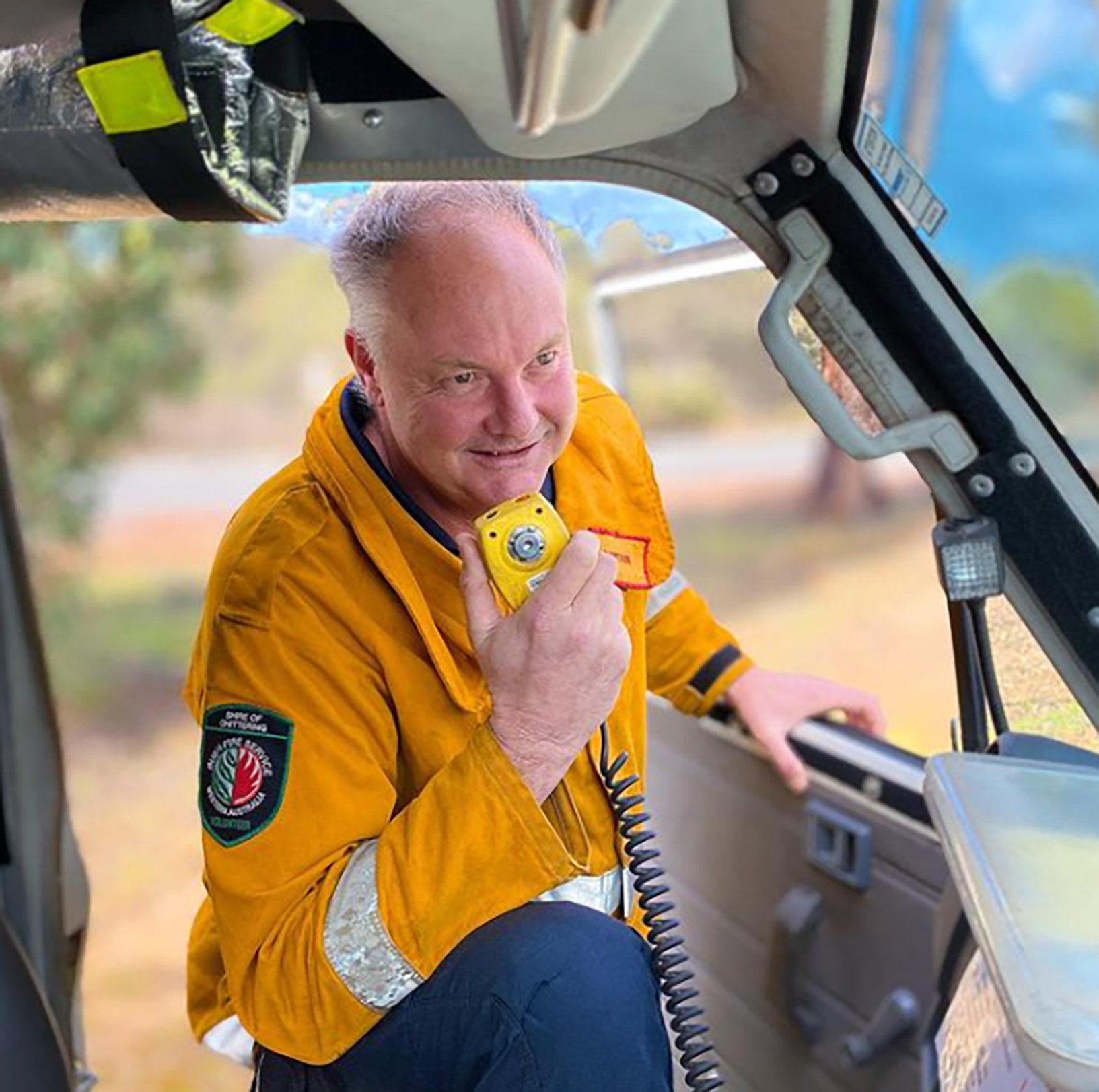 A bushfire volunteer in uniform speaking on his CB radio