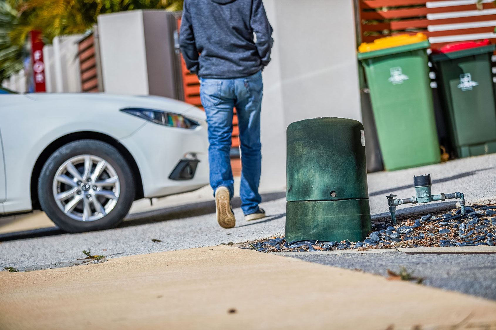 Person walking near green dome with bins in the background.