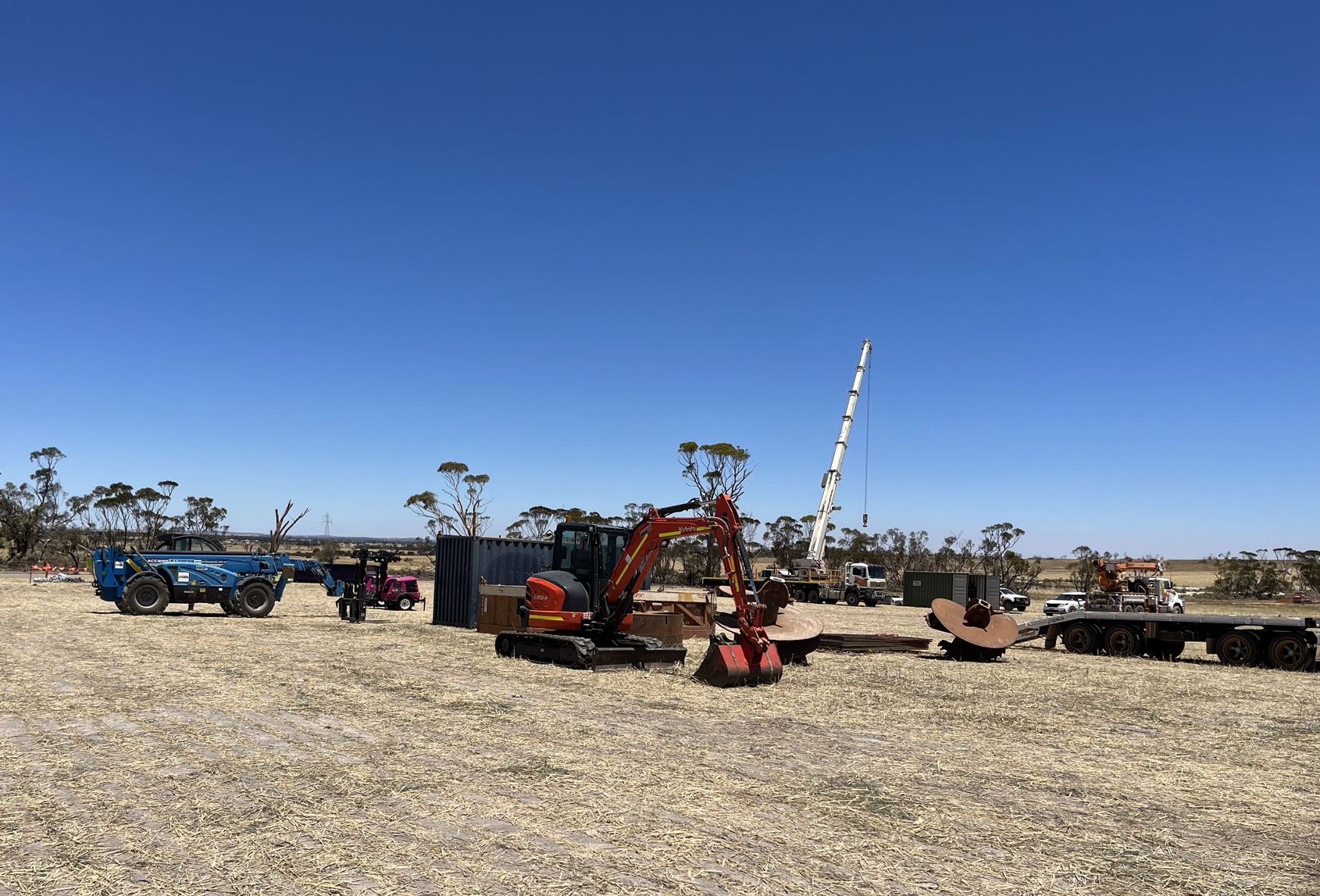 Tractors, cranes and other heavy machinery in a field as the work begins to rebuild a transmission tower