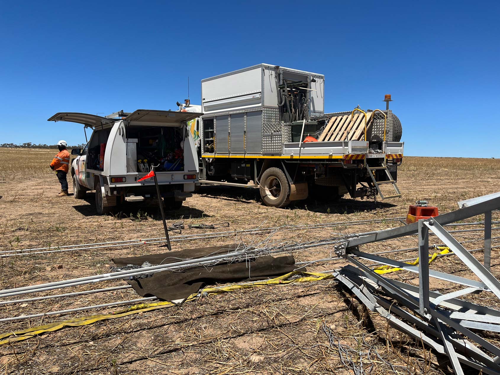 Western Power vehicles in a field with transmission lines on the ground as repair works being carried out.