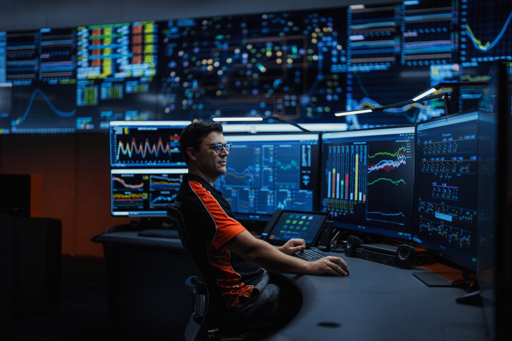 A Western Power employee sat in the Network Operations Centre with a range of screens in front of him displaying network information