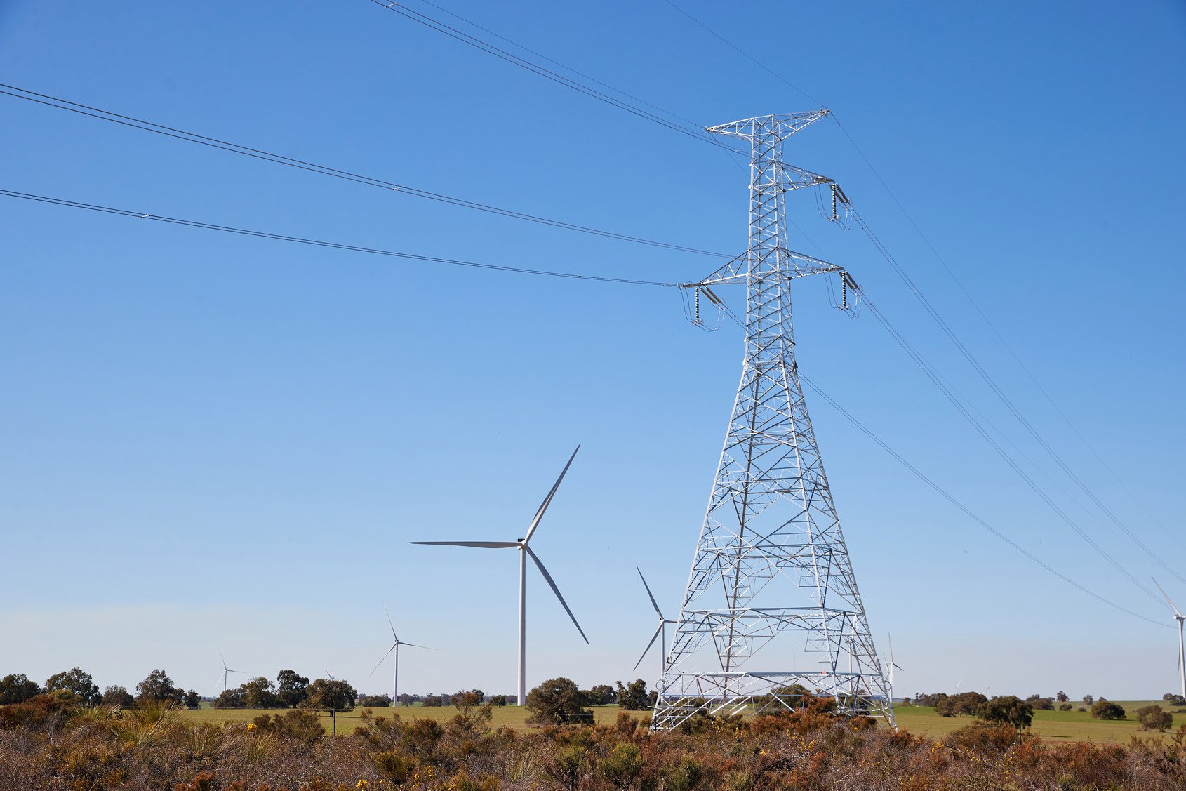 Western Power transmission tower with a wind turbine in the background