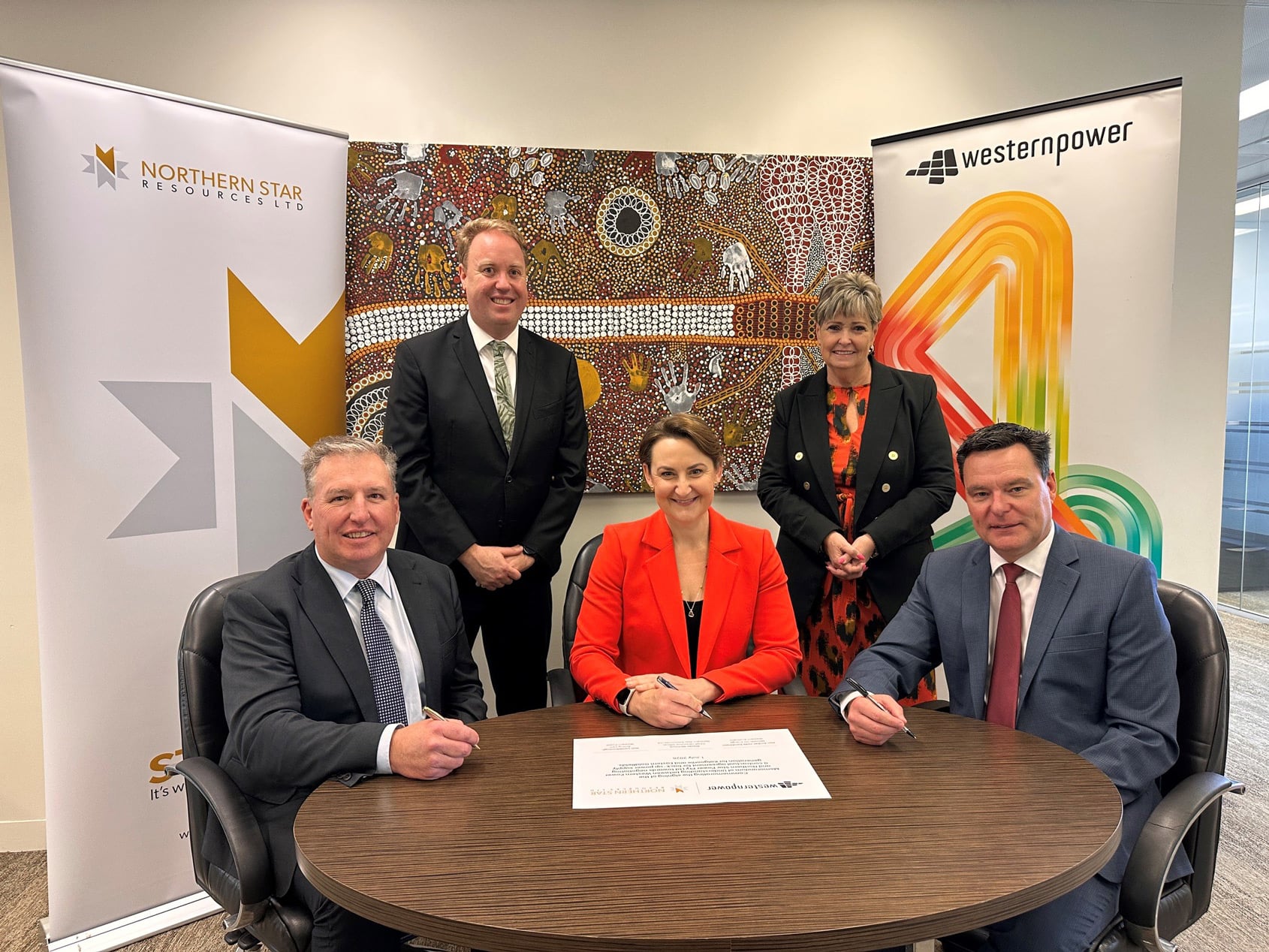 Five people sitting around a table while signing a MOU, with Northern Star Resources and Western Power banners on either side.