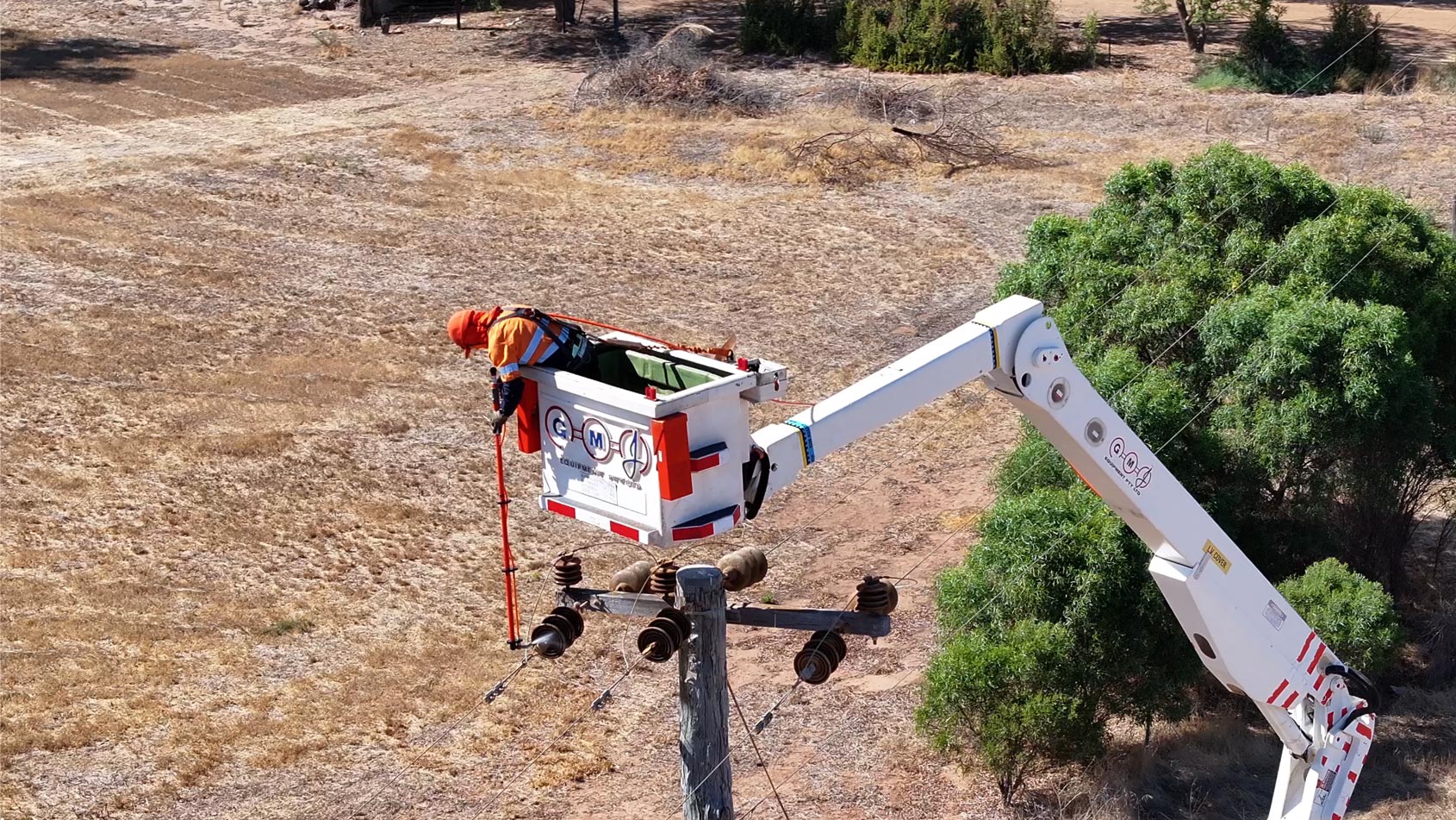 Western Power crew member in an elevated work platform siliconing a power line