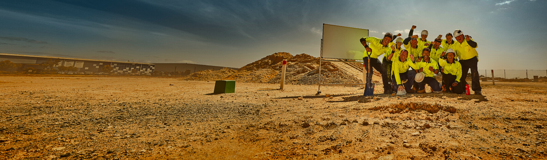 Crew on construction site in front of white board celebrating and cheering.