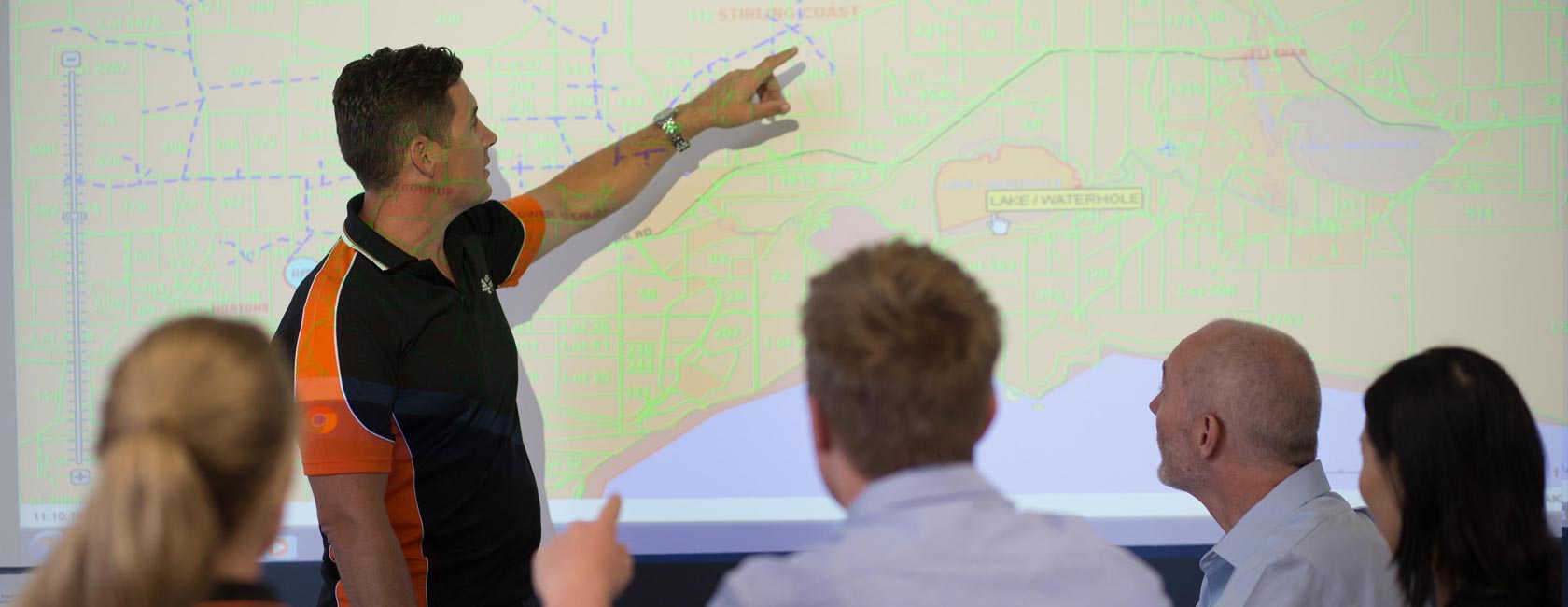 Western Power facilitator pointing to a location on a map in front of audience in an office.