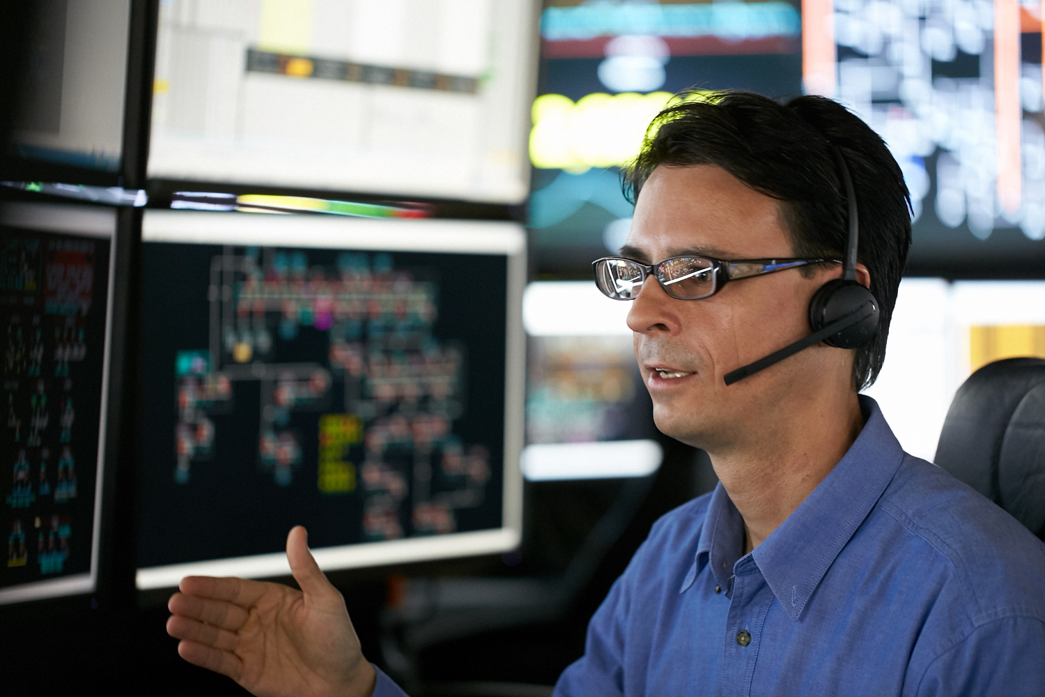 A Western Power employee sat in the Network Operations Centre with a range of screens in front of him displaying network information