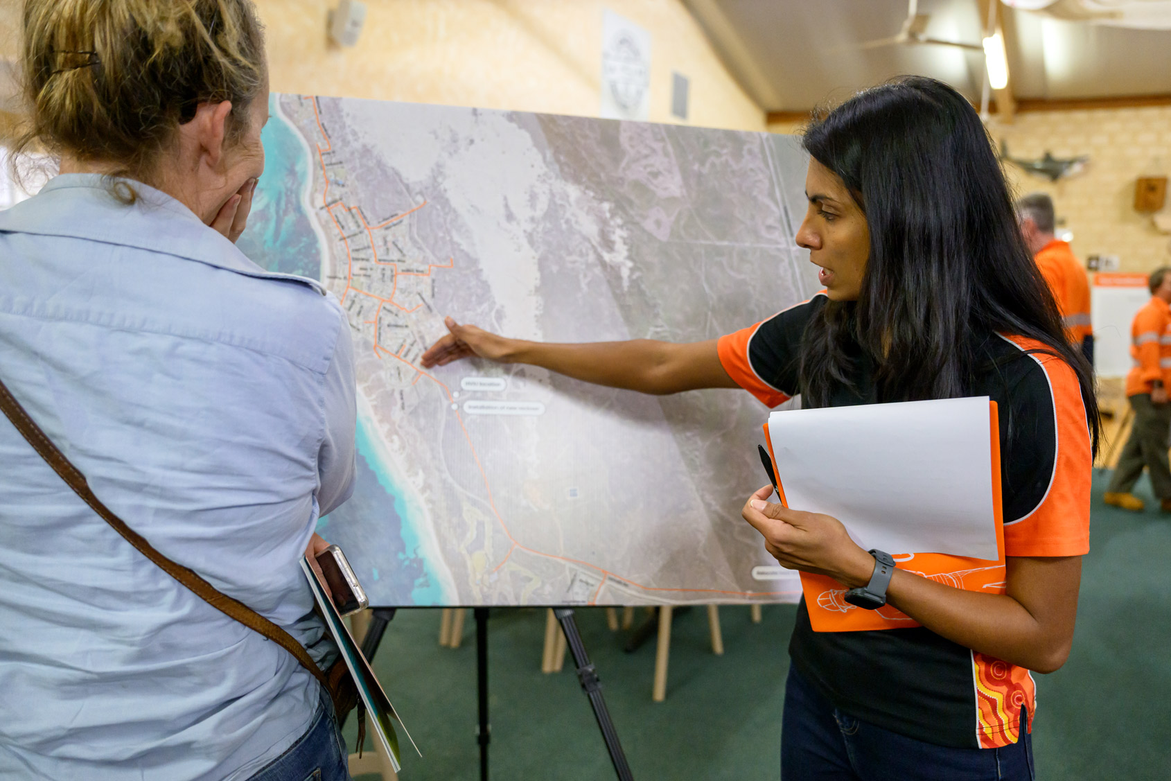 A Western Power employee stood next to a local resident and pointing on map at a community meeting in Lancelin