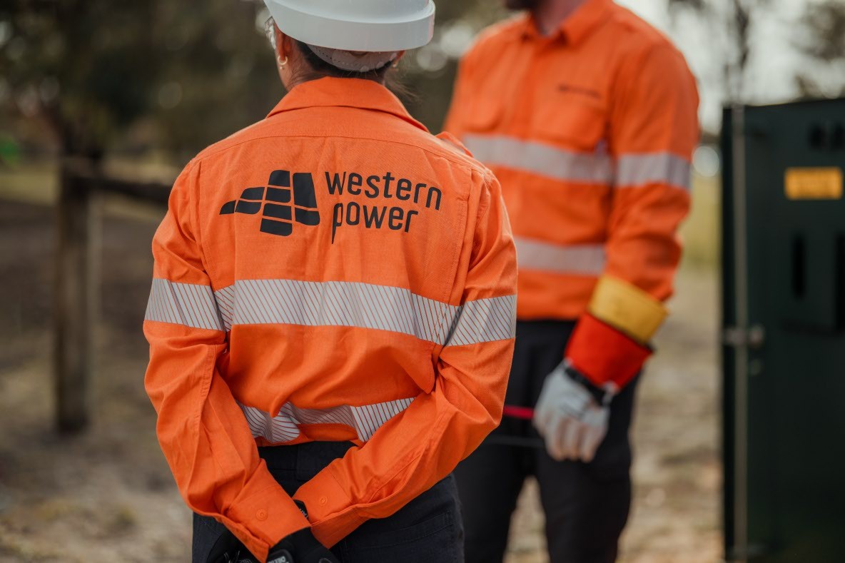 Western Power workers in high-visibility safety clothing standing near electrical infrastructure.