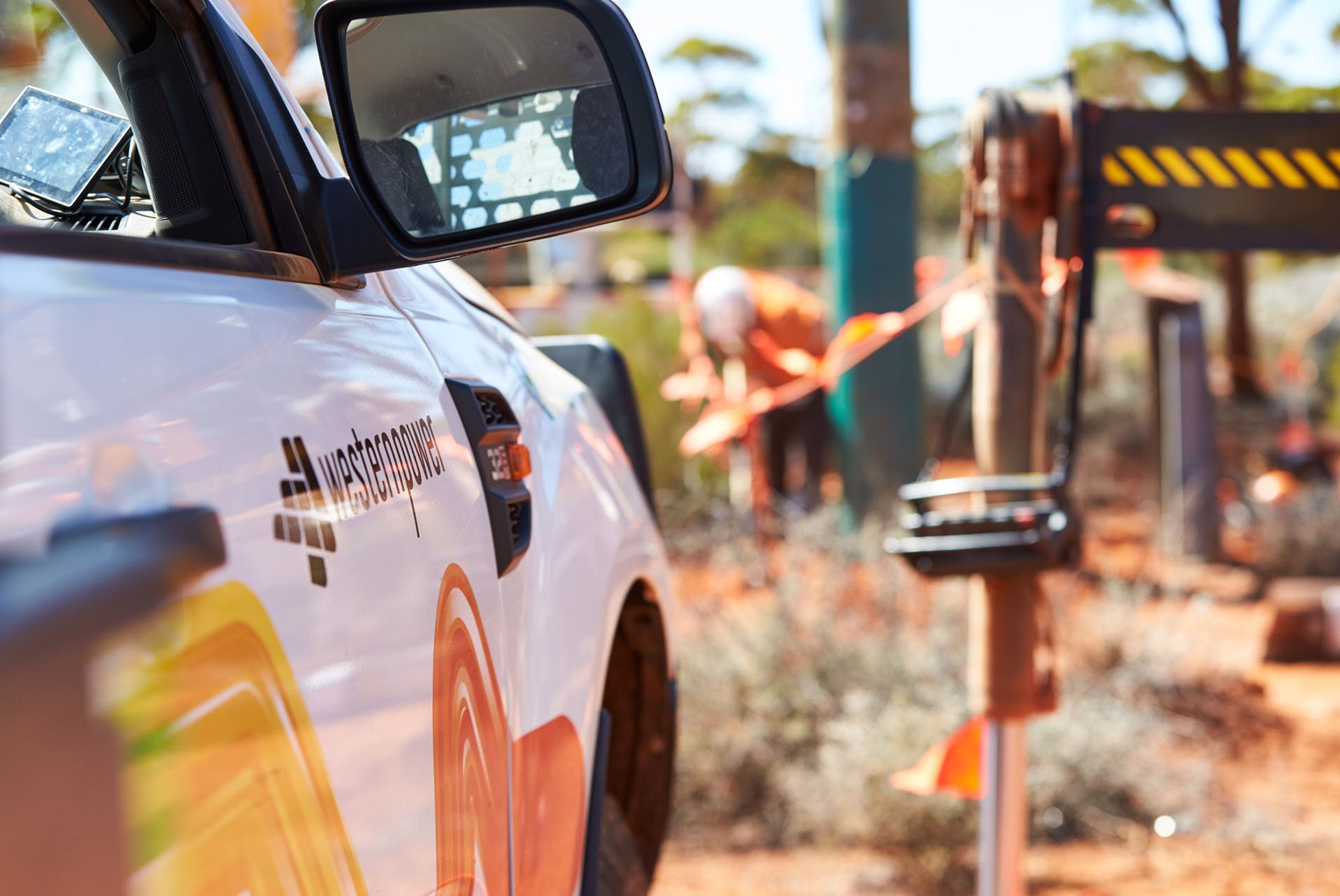 A Western Power vehicle with crews working in the background on damaged infrastruture