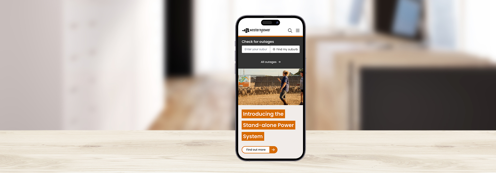 A mobile phone resting on a table displaying the new Western Power website on the screen.