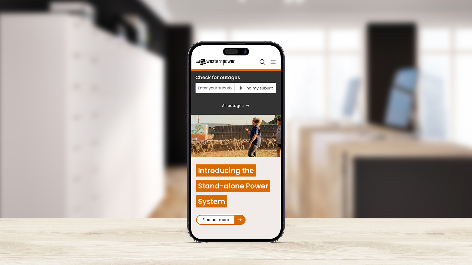 A mobile phone resting on a table displaying the new Western Power website on the screen.