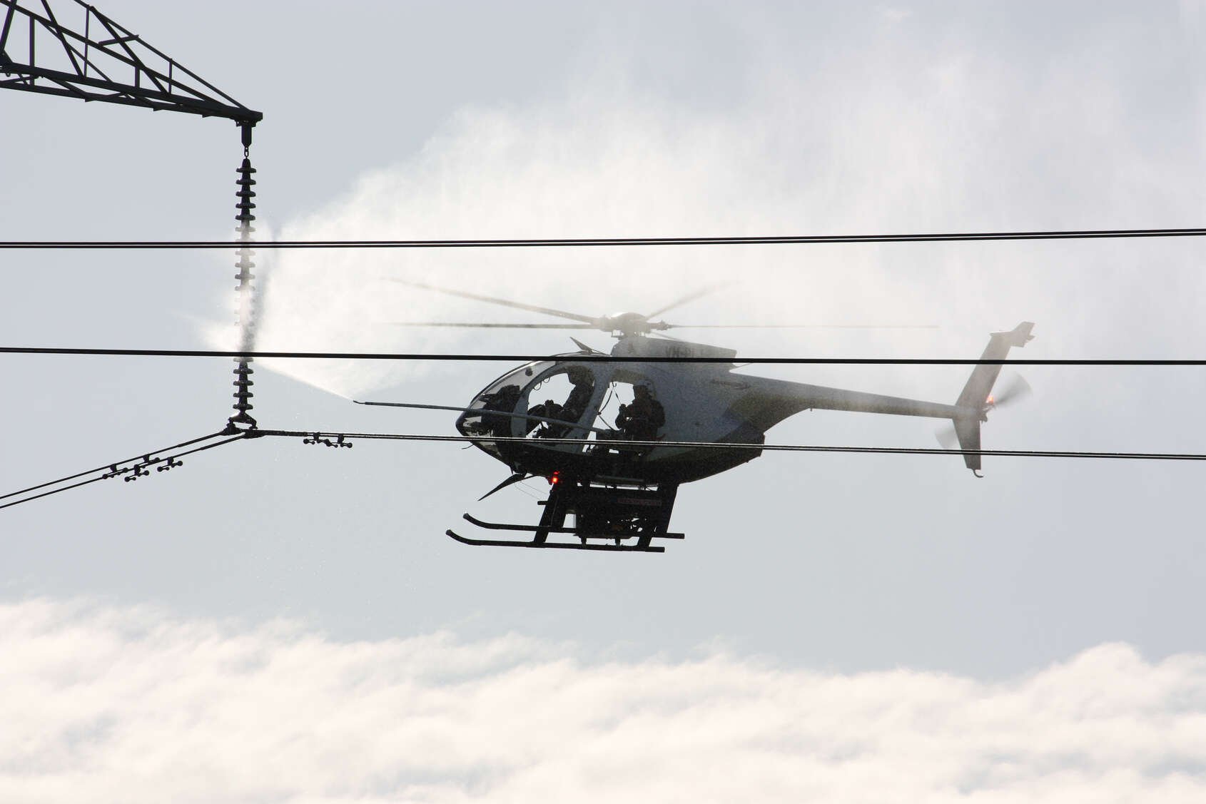 A helicopter carry out line washing on some electricity lines