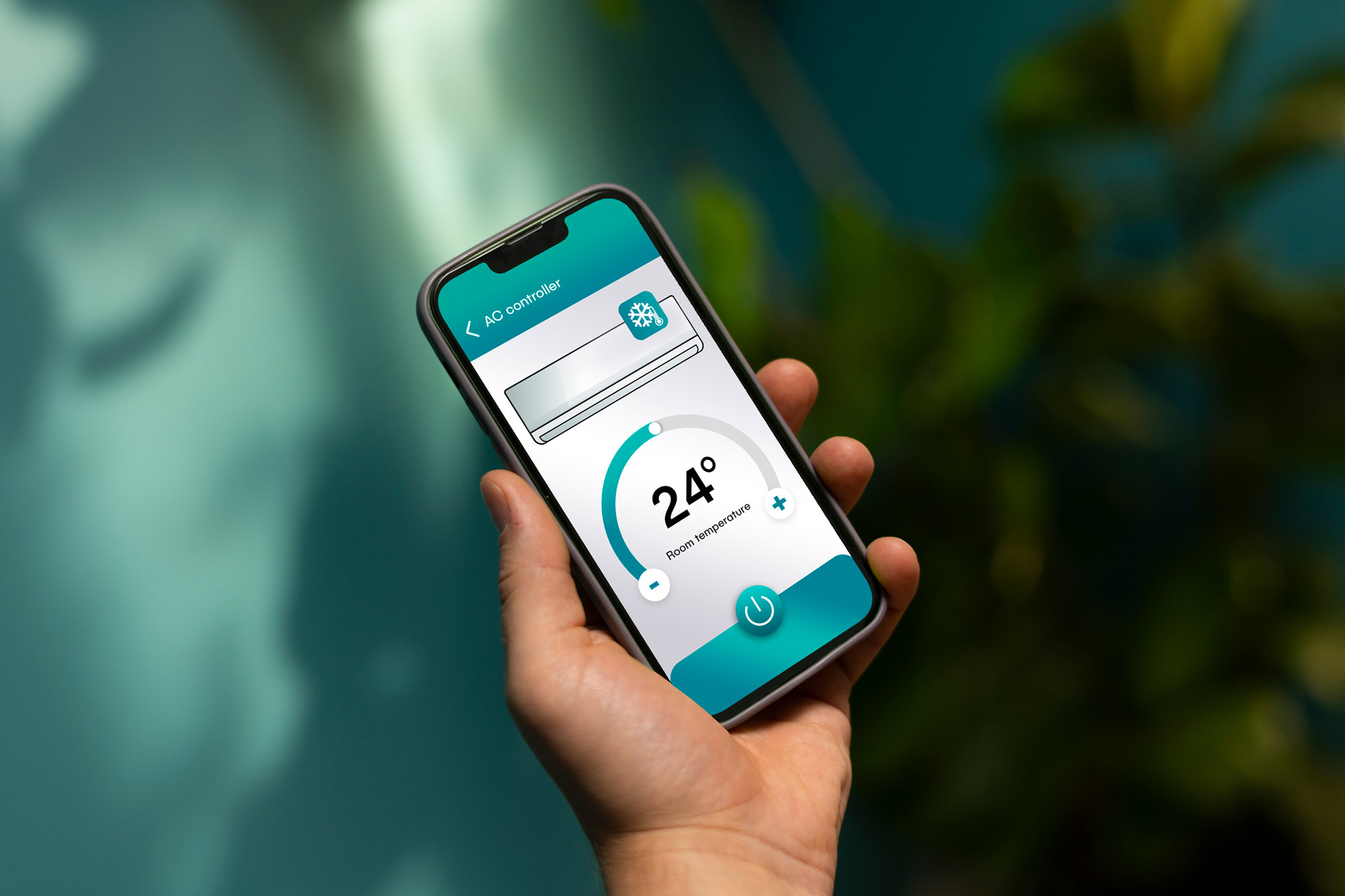 A hand holding a mobile phone with the air conditioner temperature displayed on the screen.