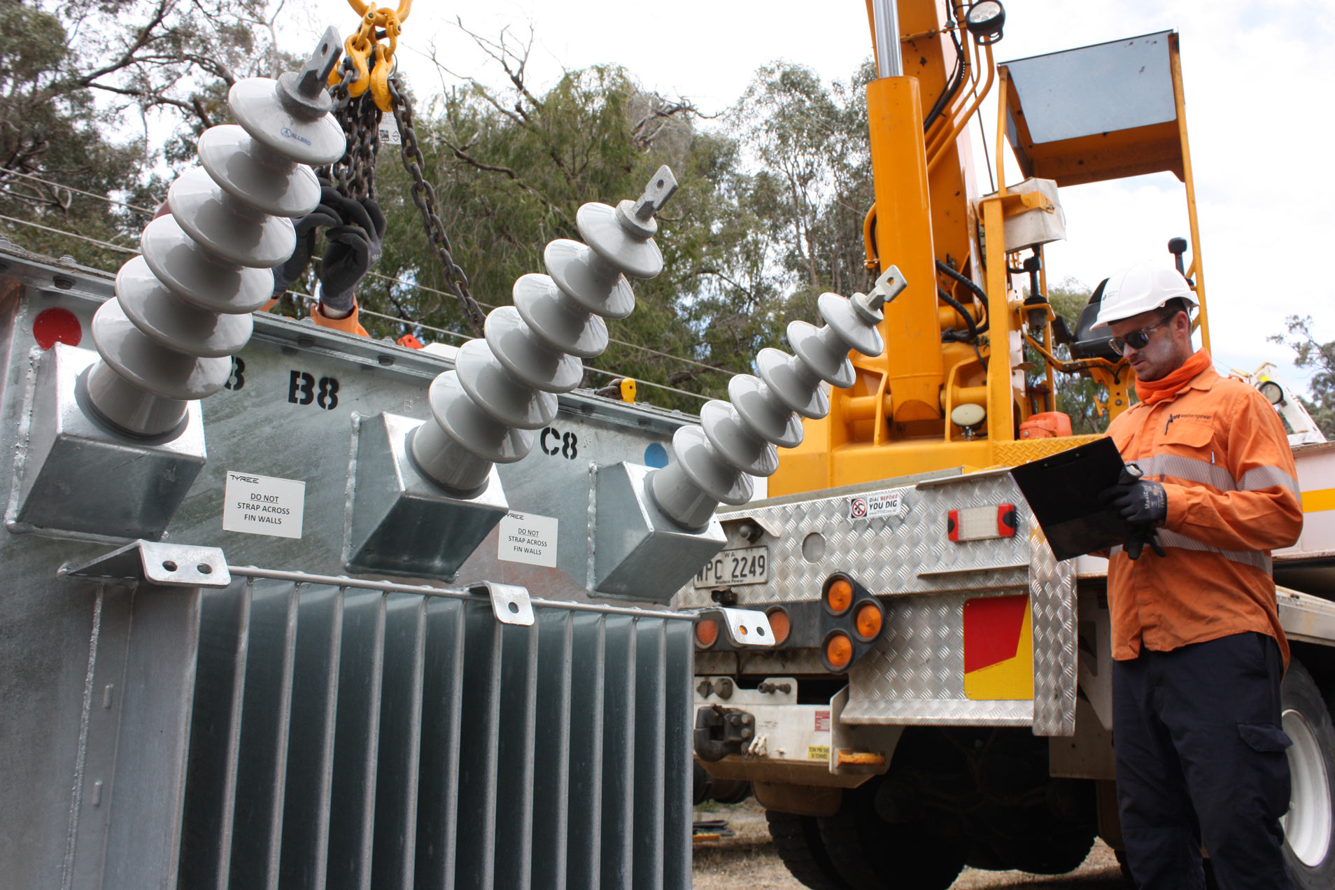 A Western Power crew member holding a clipboard stood in front of a transformer