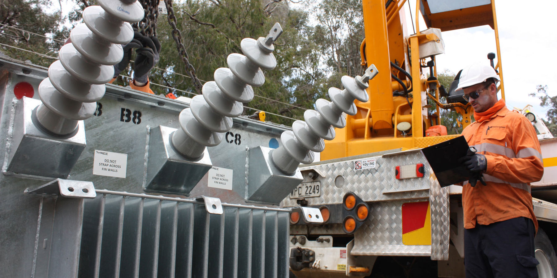 A Western Power crew member holding a clipboard stood in front of a transformer