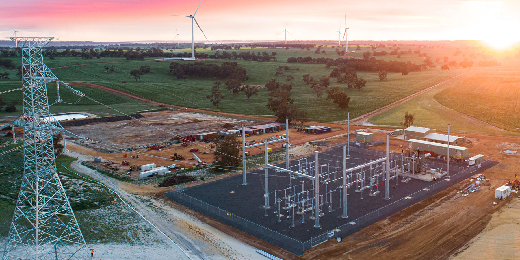 Electricity substation with wind turbines in the distance at sunset