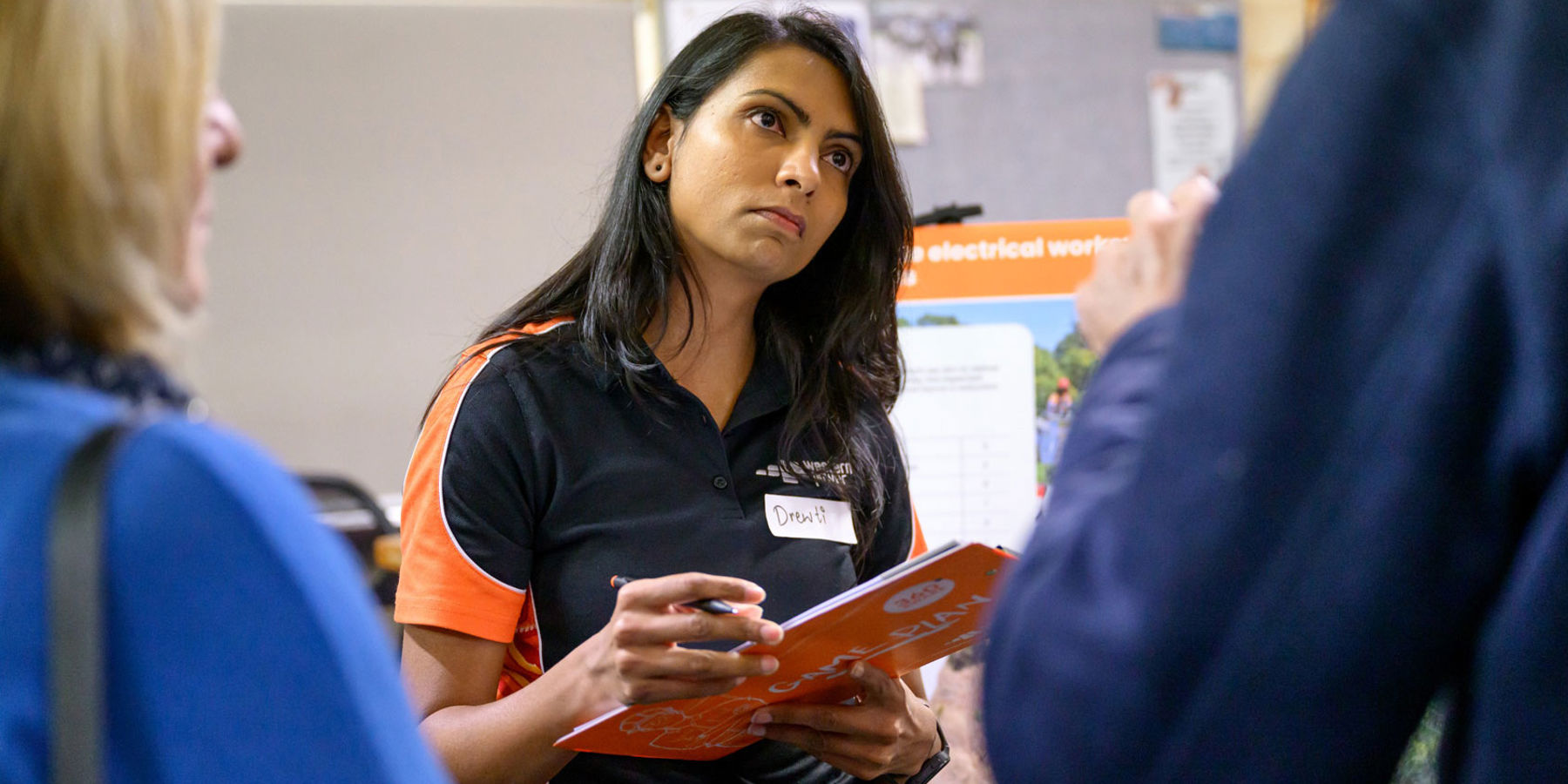 Western Power employee holding a clipboard while listening members of the community