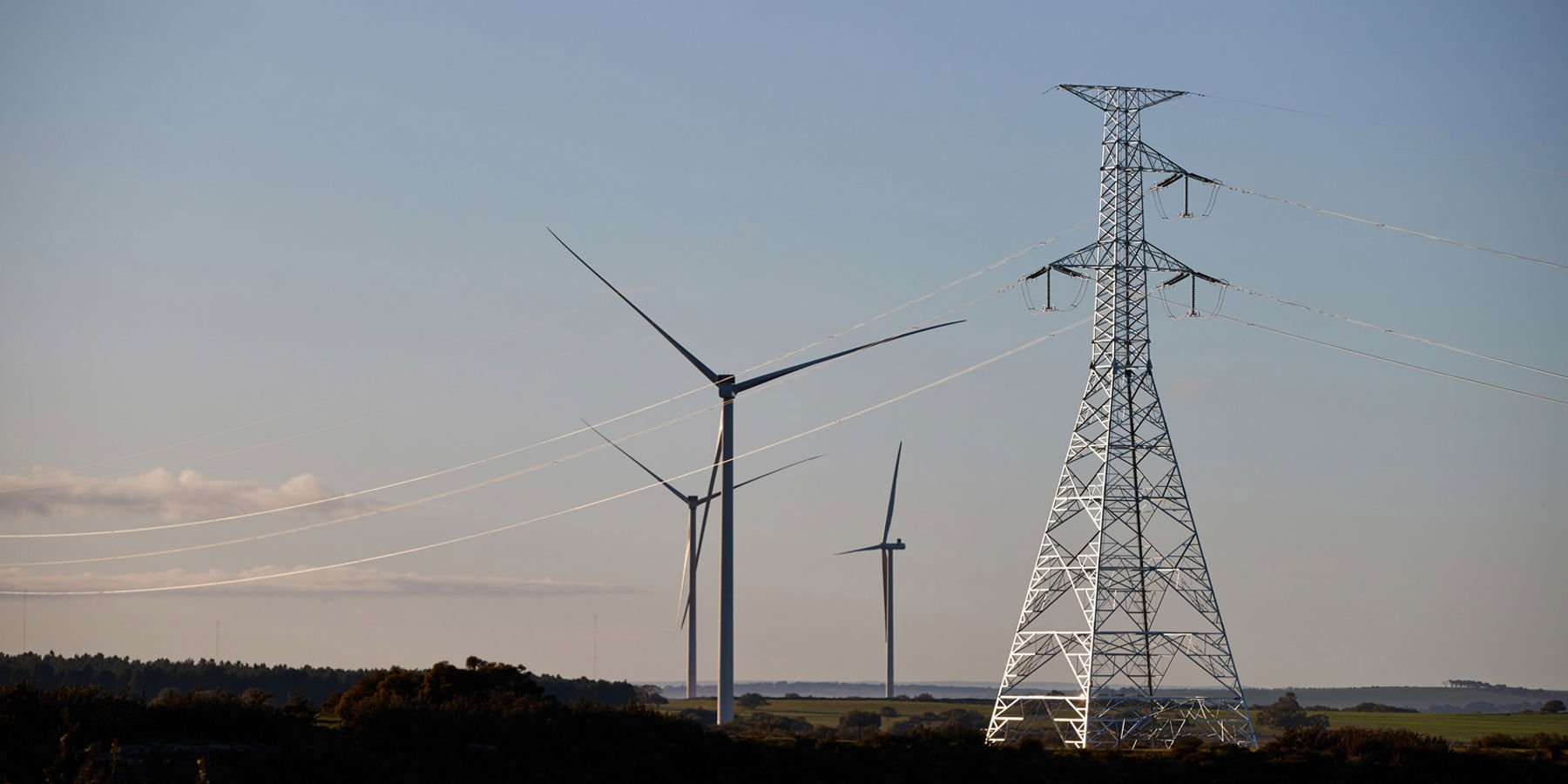 Transmission tower with wind turbines in the background